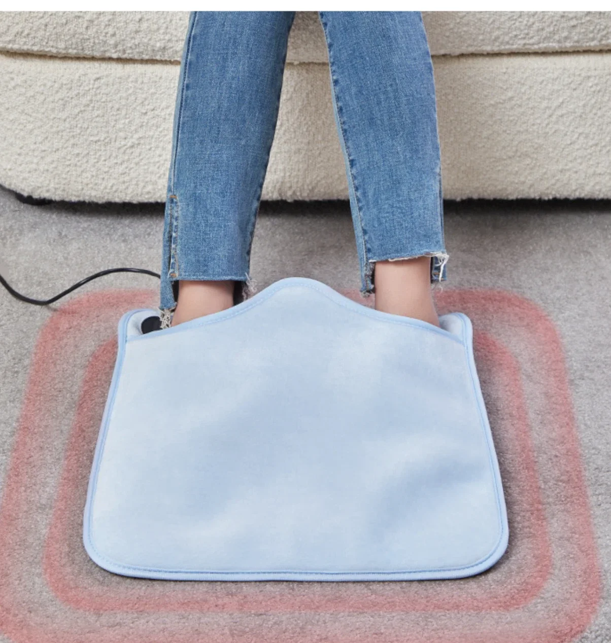 Feet tucked into the light blue heated foot warmer pad on a rug
