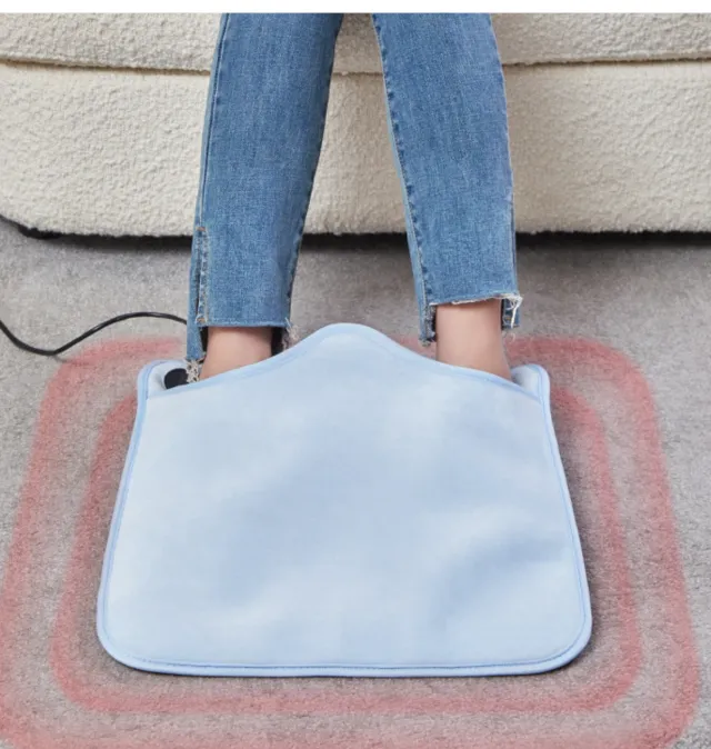 Feet tucked into the light blue heated foot warmer pad on a rug