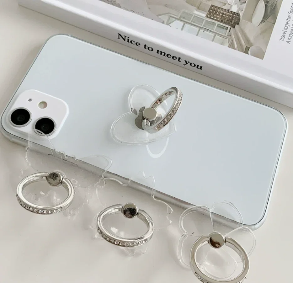 Clear rhinestone ring holders in heart, flower and butterfly shapes, one stuck to a white phone