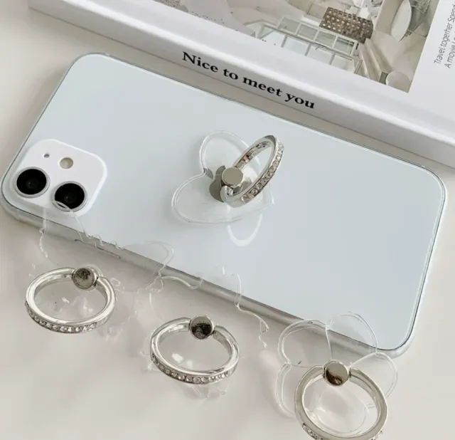 Clear rhinestone ring holders in heart, flower and butterfly shapes, one stuck to a white phone