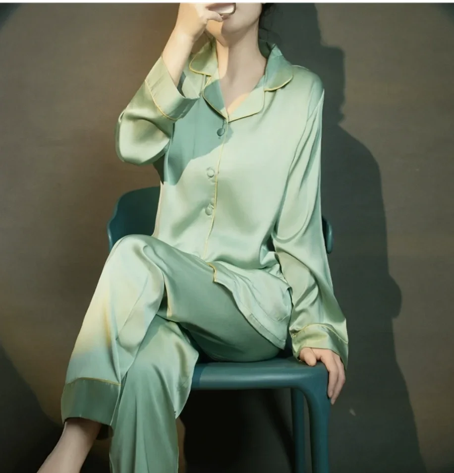 Woman seated wearing the sage silk pajama set with gold piping