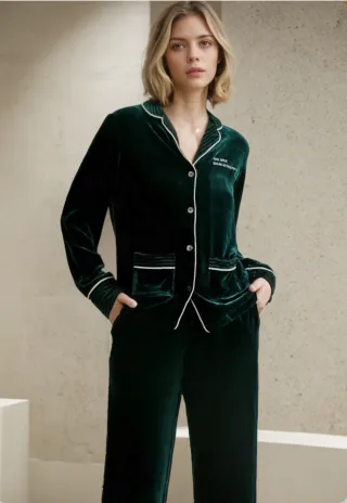 Woman wearing the dark green velvet pajama set with white piping