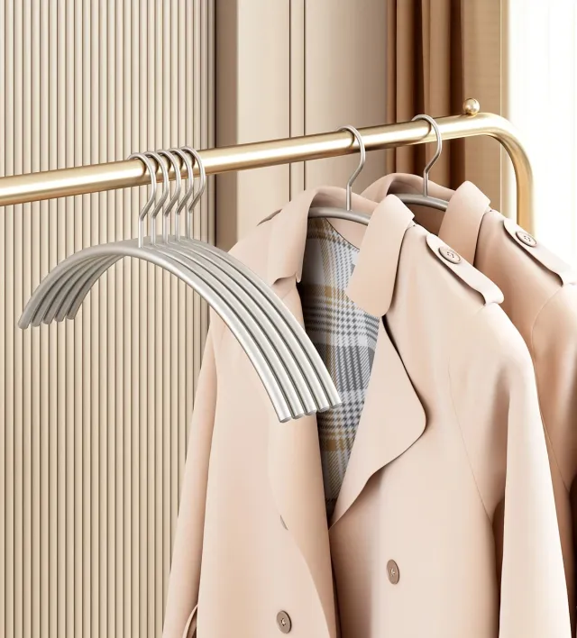 Pearl-nickel steel hangers holding coats on a brass rail