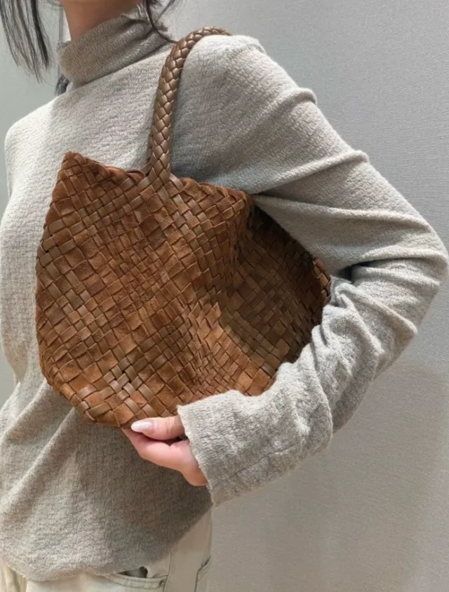 Woman carrying the cognac hand-woven leather tote on her shoulder